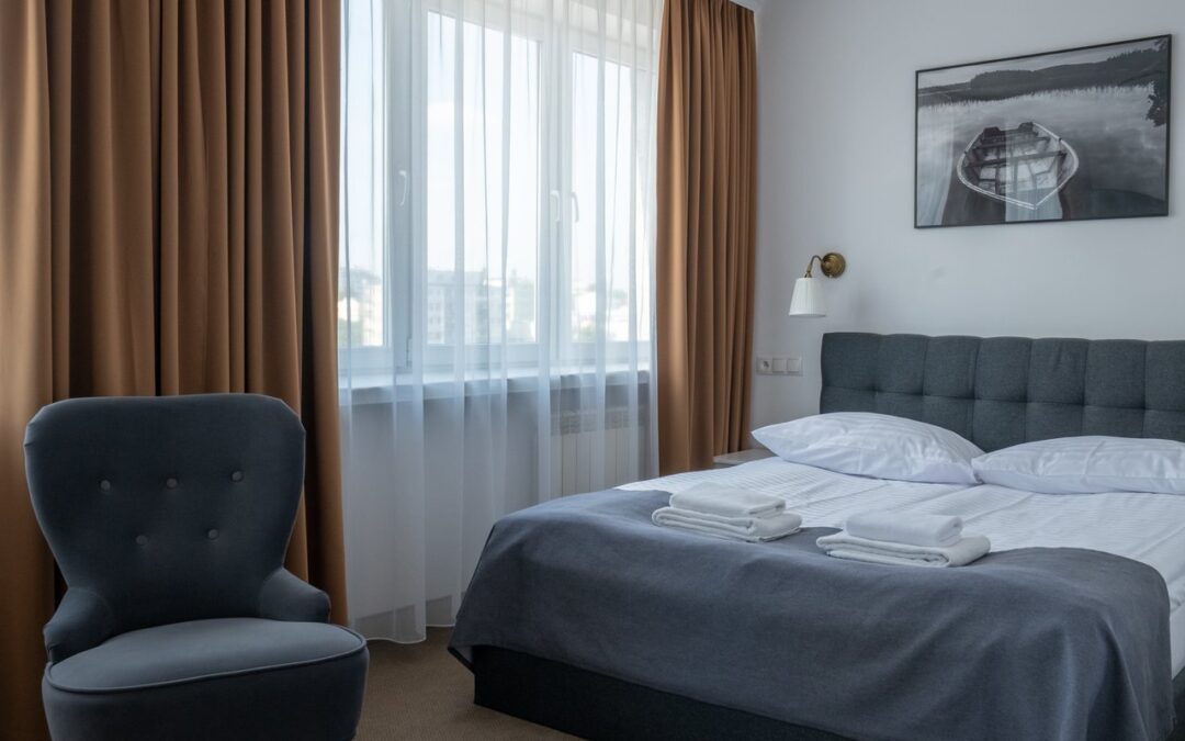 Fotel i łóżko małżeńskie w sypialni apartamentu